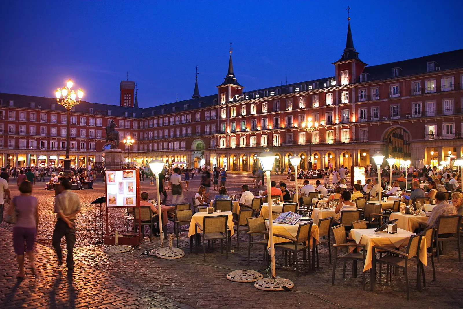 Cafe tables set outdoors at dusk in Plaza Mayor in Madrid, Spain. The photo was not taken in High Point.